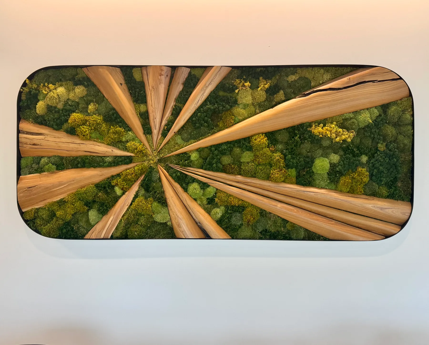 A moss panel with natural wood set in a sunburst