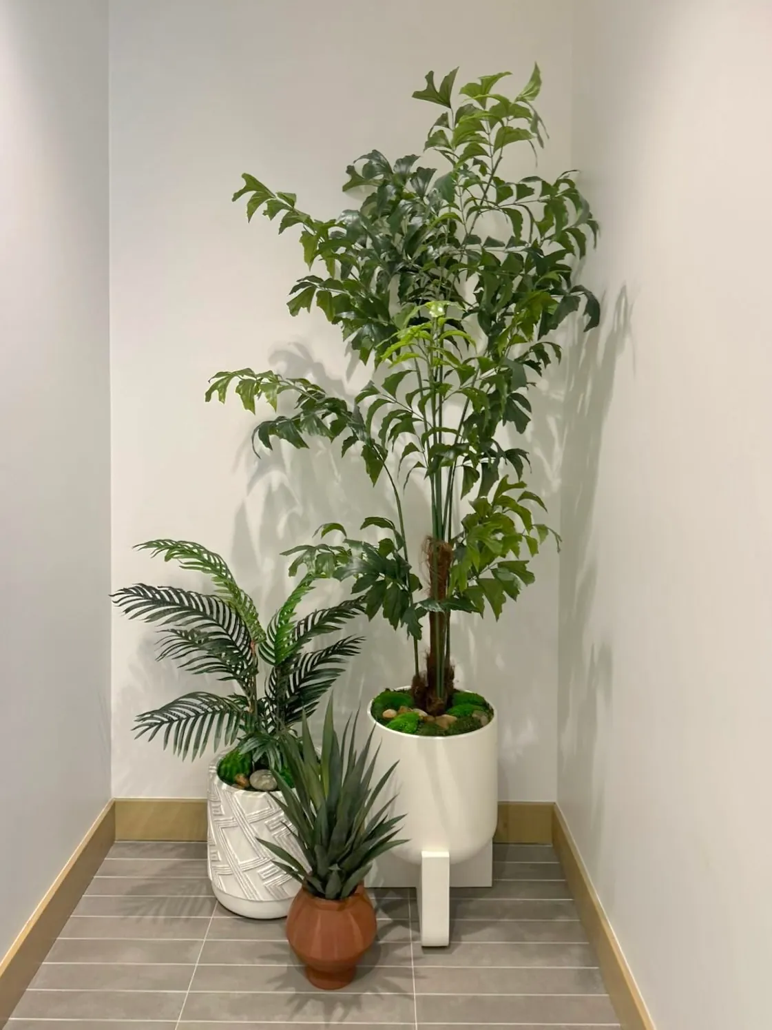 A faux tree and palm in a corner